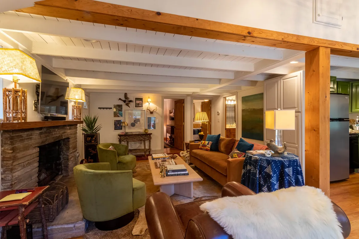 A spacious communal living area featuring two cozy sofas, a central coffee table, a stone fireplace, and carefully chosen artwork. The arrangement encourages conversation and family gatherings, with ambient lighting enhancing the warm, welcoming mood.
